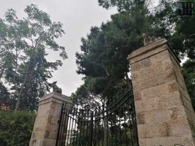 Un edificio di cui sono rimasti il muro perimetrale in pietra e il cancello di ingresso racchiuso da due colonne...